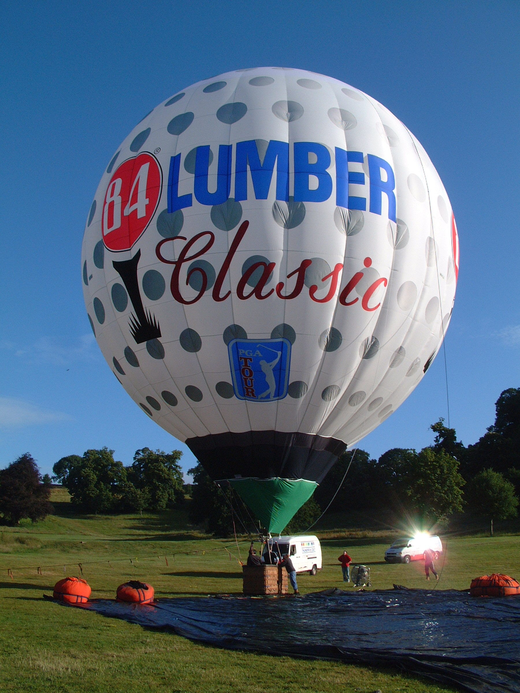 Sphere-90 with golf ball artwork and 84 lumber logo special shape Cameron hot air balloon on ground