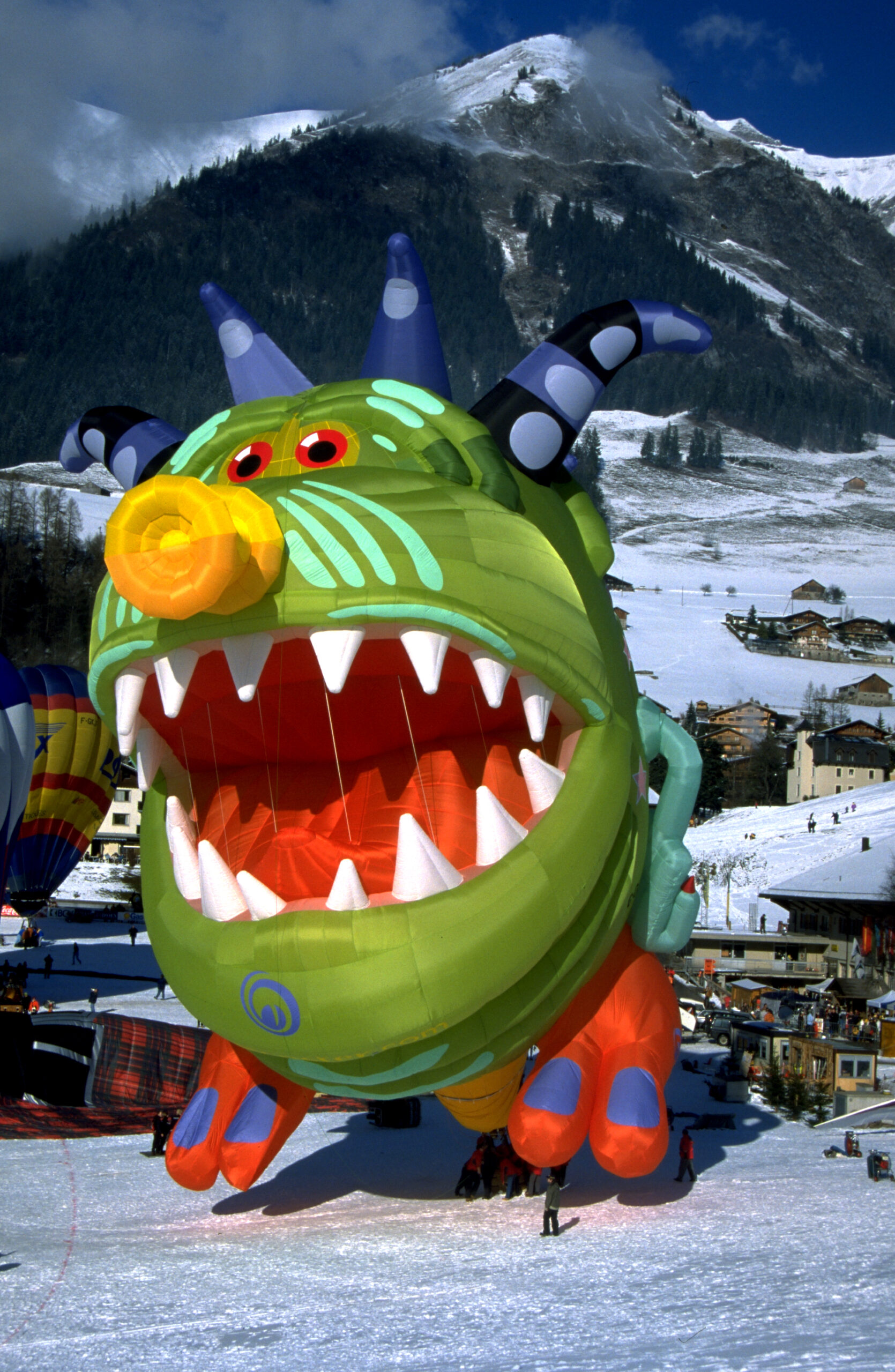 Monster special shape Cameron hot air balloon in snow in front of mountain landscape