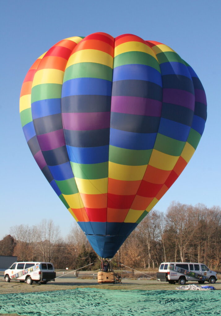 Cameron O-105 hot air balloon with a rainbow pattern on ground