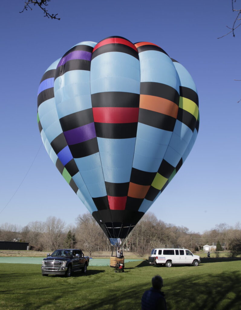 Cameron O-140 hot air balloon on ground in sunny landscape