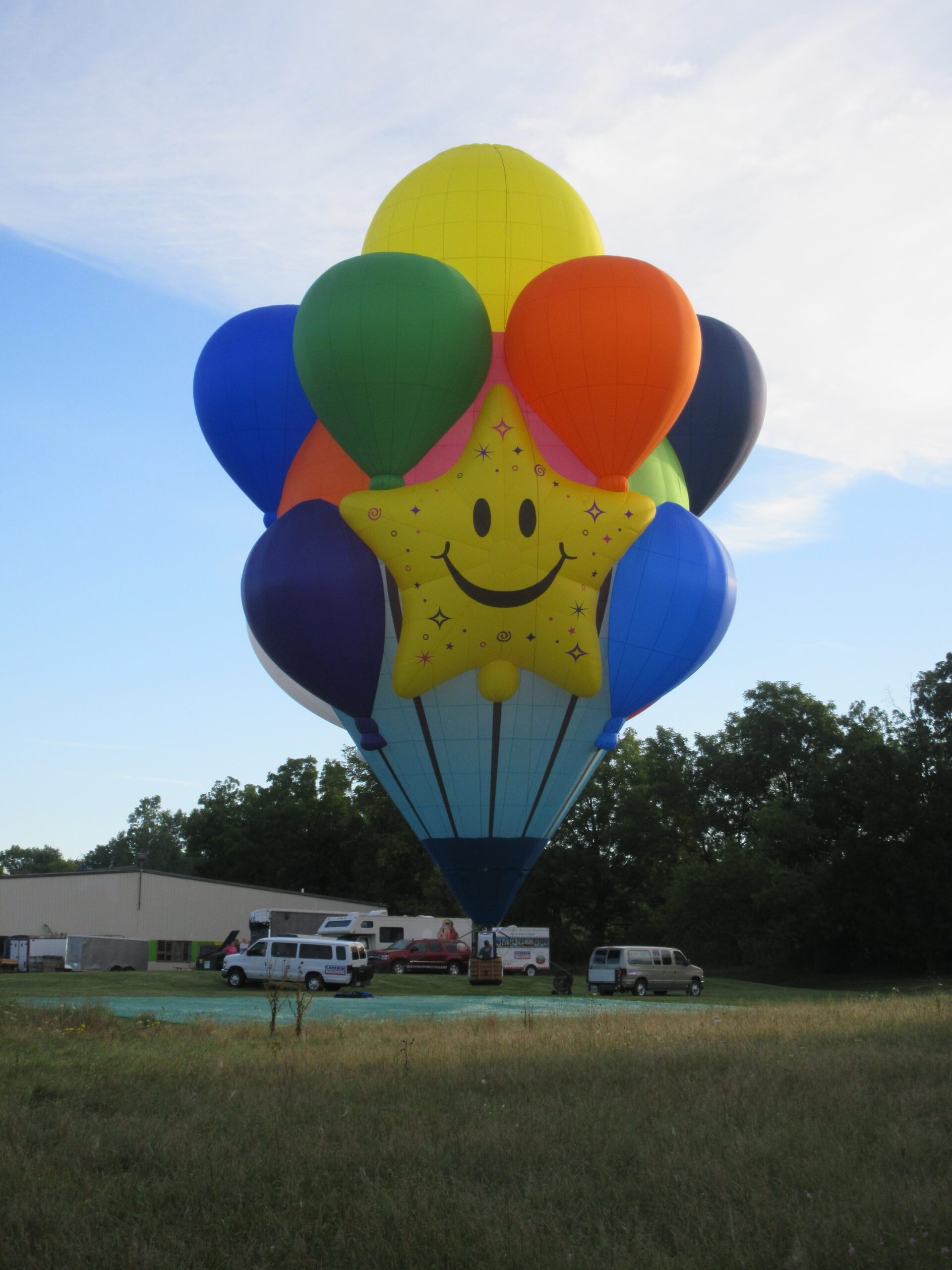 Multi-colored party balloon with smiley face artwork special shape Cameron hot air balloon on ground