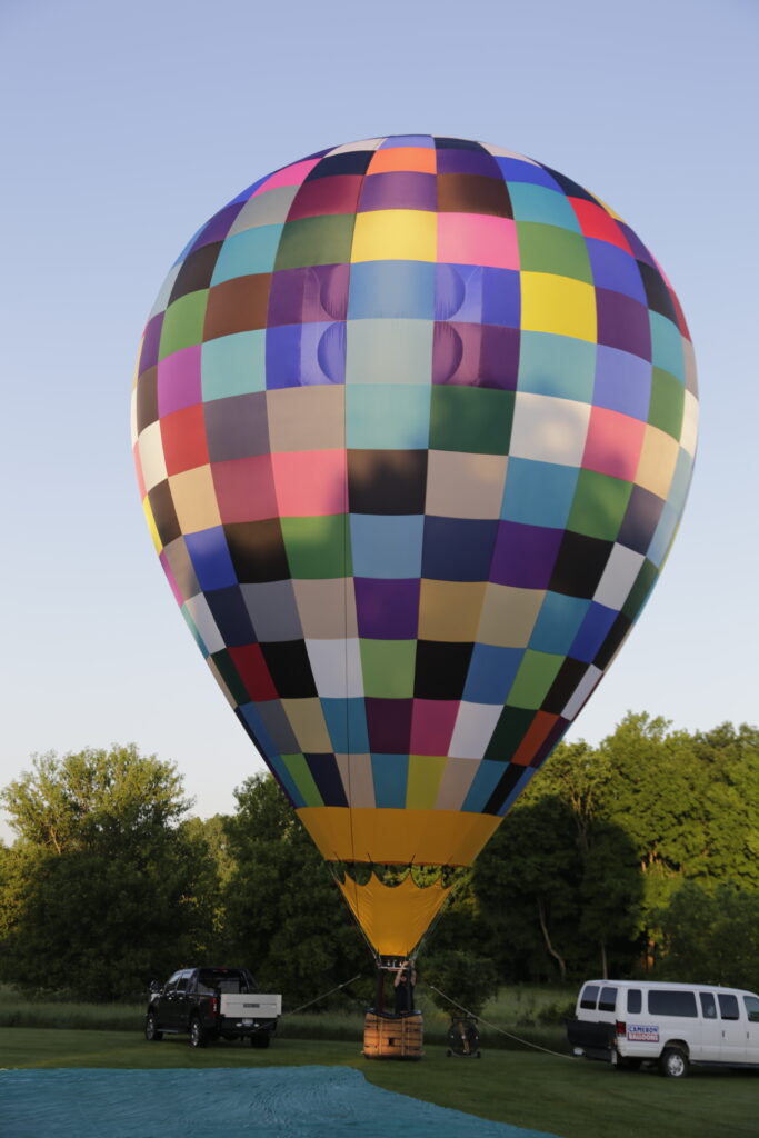 Cameron ZL-70 racer hot air balloon with many colors on ground