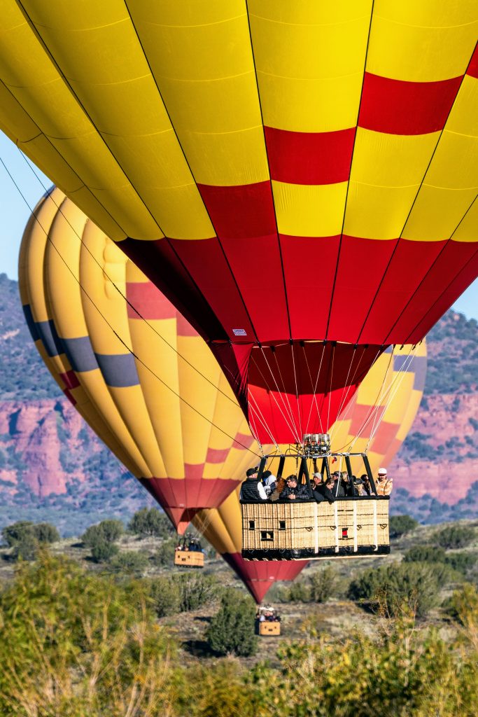 Three Cameron A-Type hot air balloons flying over a desert landscape