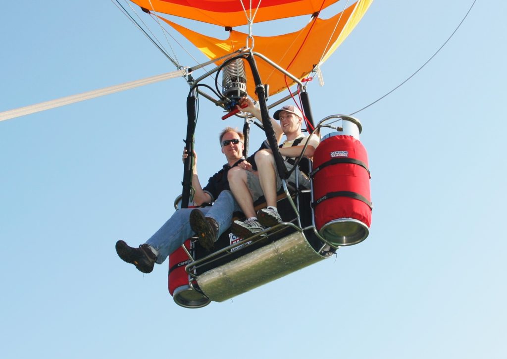 Two people flying in a Cameron Duo Chariot hot air balloon lower end