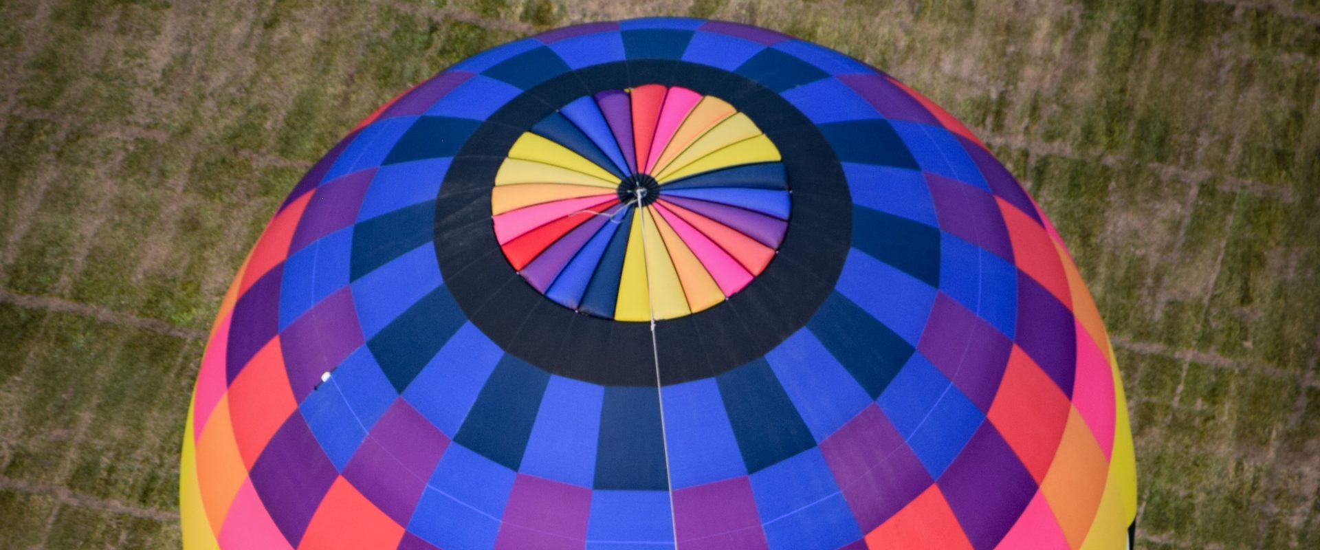 Cameron ZL-60 hot air balloon flying over a cut grass field