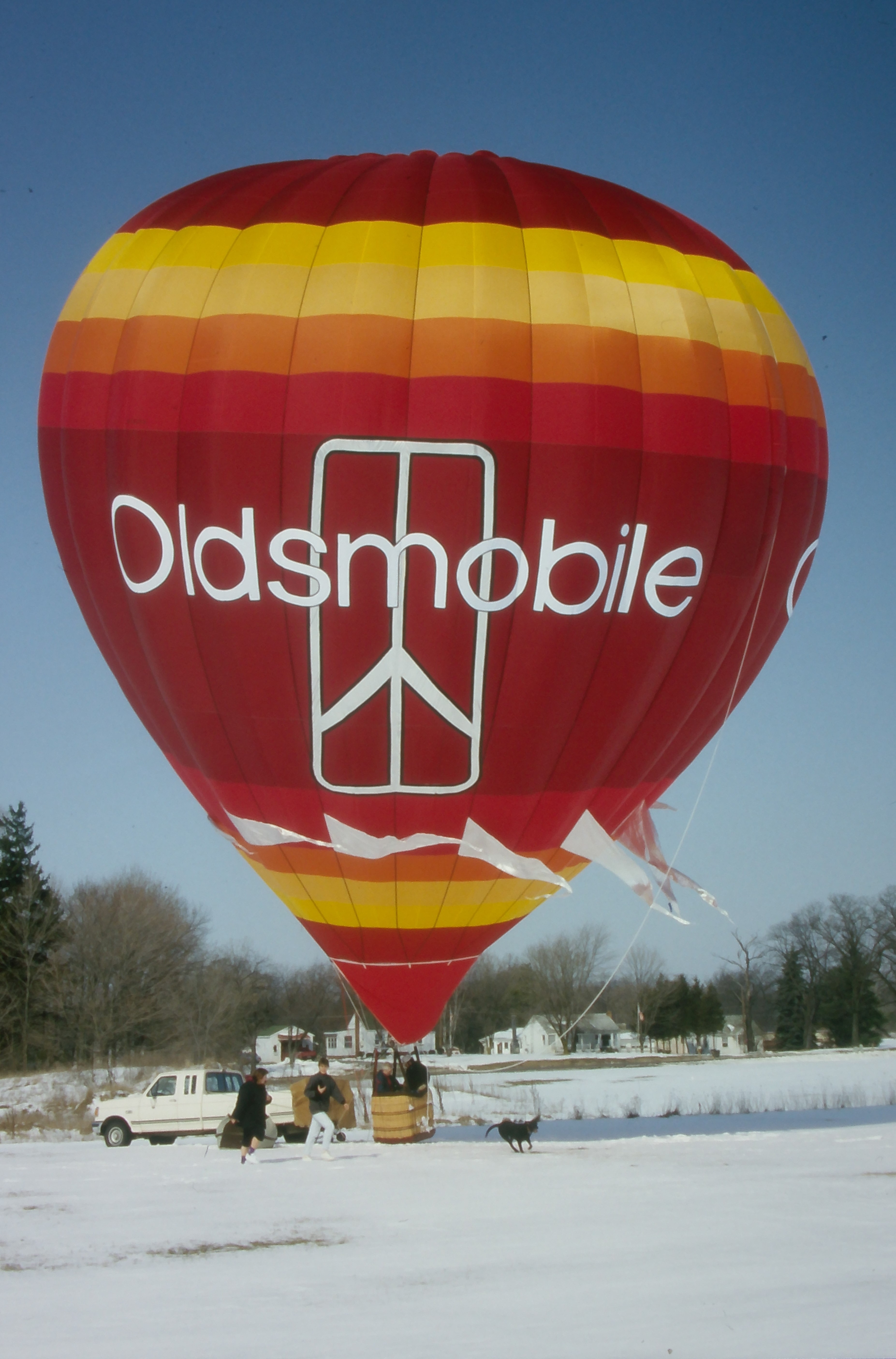 Cameron N-77 hot air balloon with Oldsmobile branding on ground in snow